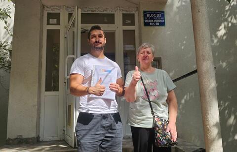 Operator Compania DDD la intrarea unui bloc, cu procesul-verbal semnat de reprezentantul asociației