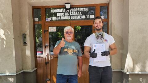 Operator Compania DDD la intrarea unui bloc, cu procesul-verbal semnat de reprezentantul asociației